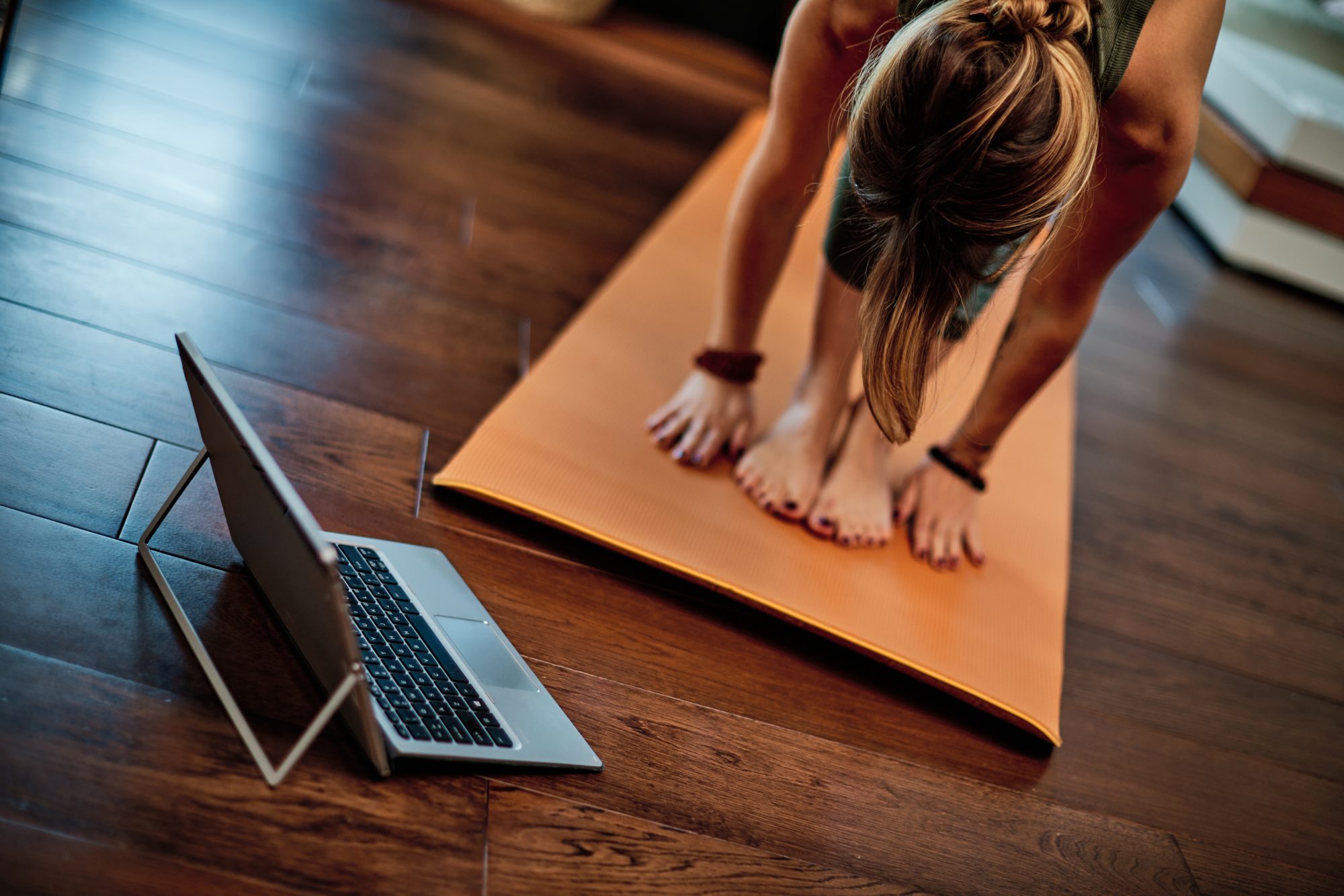 Frau praktiziert Online-Yoga zu Hause auf einer Matte – achtsame Praxis vor dem Laptop