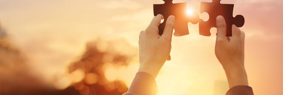 Zwei Hände halten Puzzleteile im Sonnenlicht – Symbol für Verbindung, Erkenntnis und inneres Wachstum bei Helena Gnaase
